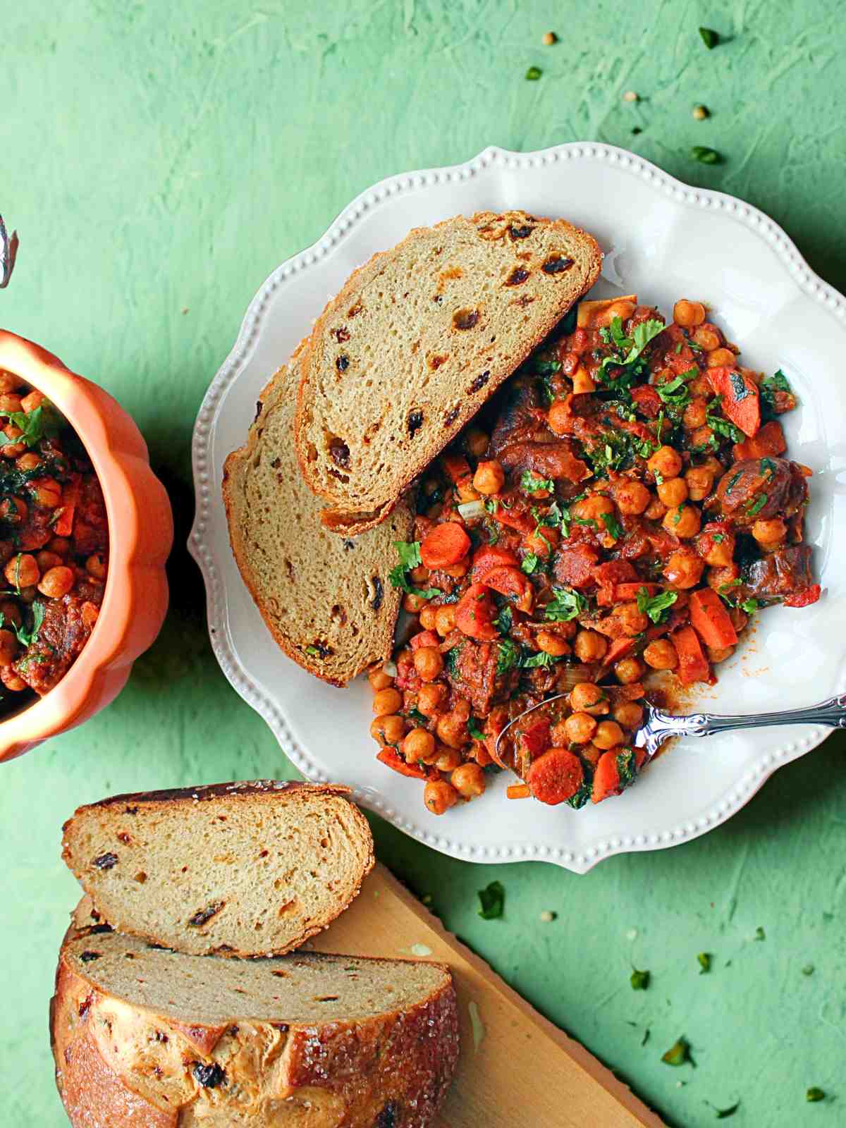 Moroccan chickpea goat stew on a serving plate garnished with cilantro and served with bread.