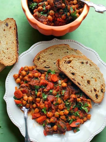 Moroccan Chickpea Goat Stew on a serving plate with crusty bread.