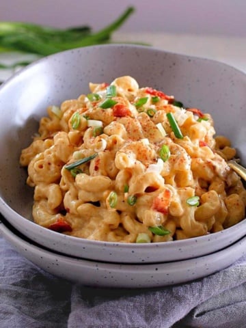 A bowl of creamy pasta garnished with bacon.