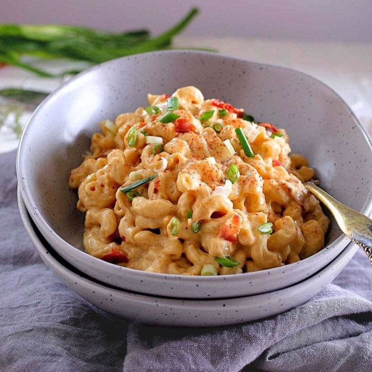A bowl of creamy pasta garnished with bacon.