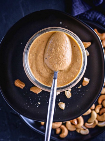 cashew pasta sauce in a mason jar scooped with a spoon.