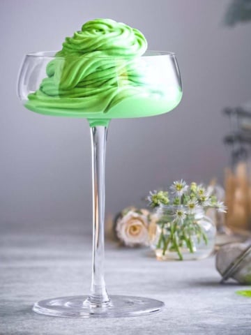 a glass filled with green ice cream.
