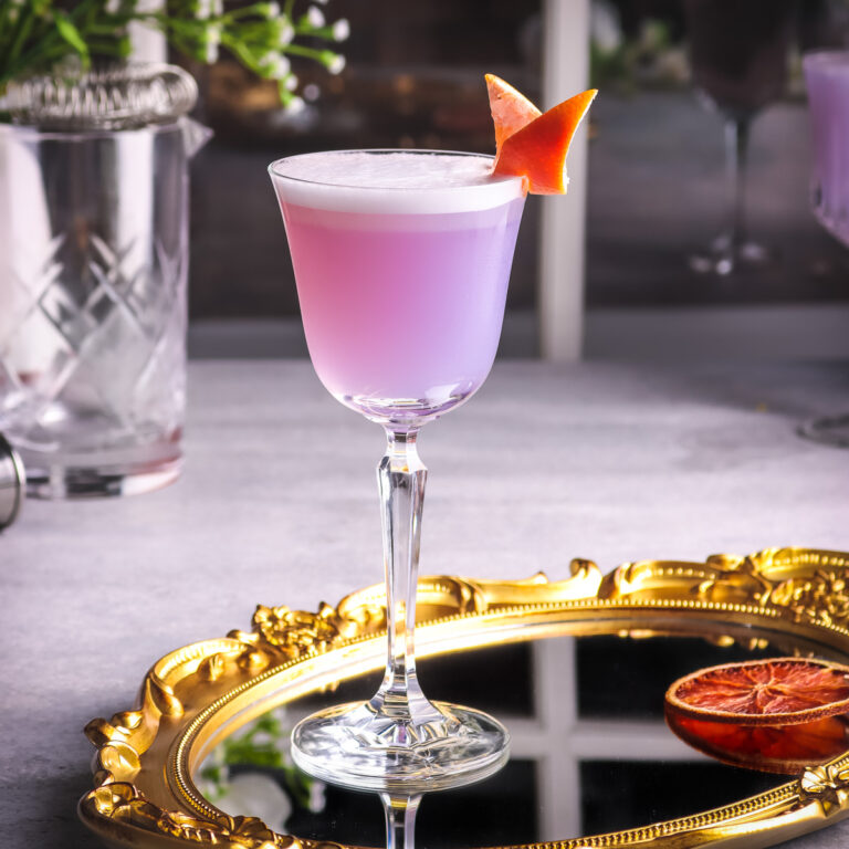 a photo of grapefruit gin cocktail on a glass tray garnished with grapefruit twist.