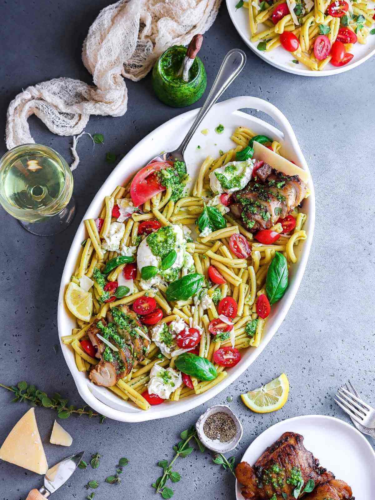 Combining the pasta with pesto and chicken.