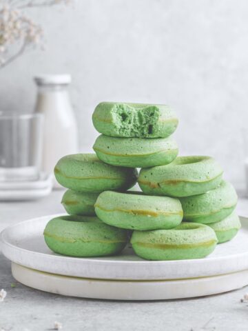 A Featured image of green donuts without glaze stacked up on a white plate