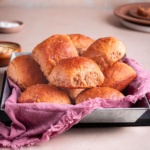 banana yeast bread roll served on a pan with kitchen towel, and a bowl of butter.