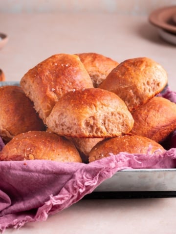 banana yeast bread roll served on a pan with kitchen towel, and a bowl of butter.