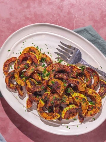 easy sautéed delicata squash on a plate with a green napkin and serving plates.