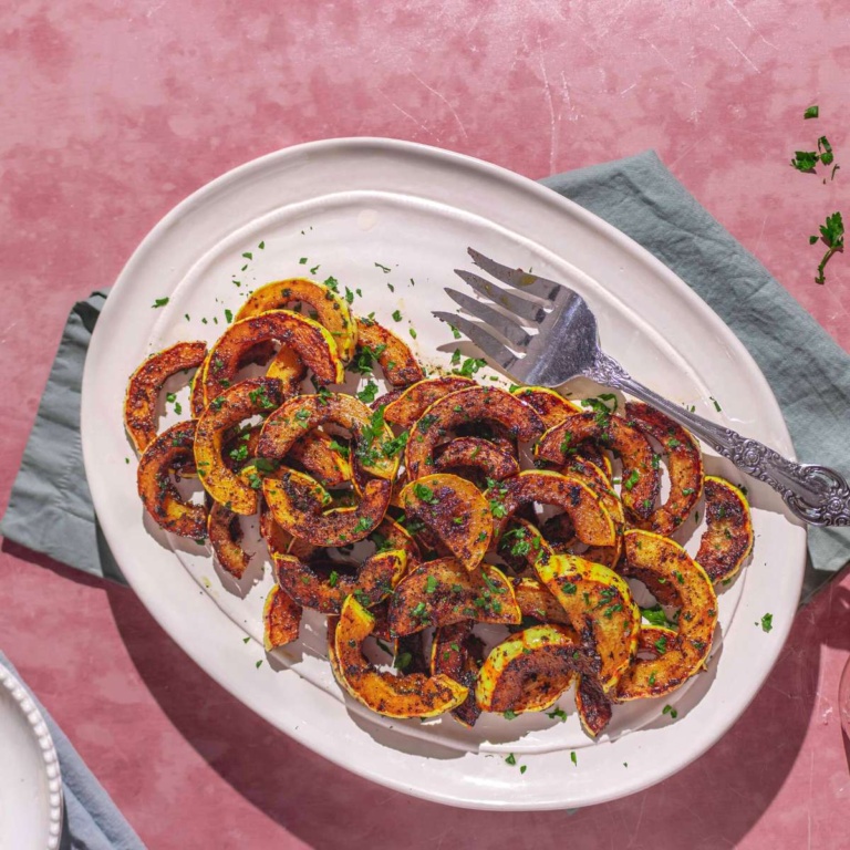 easy sautéed delicata squash on a plate with a green napkin and serving plates.