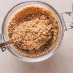 homemade pecan flour in a jar heaped on a silver spoon.