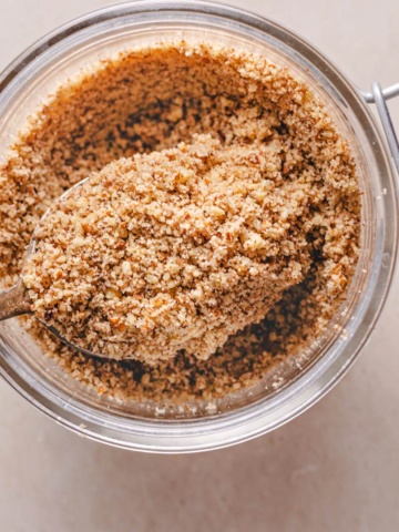 homemade pecan flour in a jar heaped on a silver spoon.