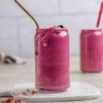 oat milk smoothie in a tall glass cup with straw.