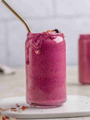 oat milk smoothie in a tall glass cup with straw.