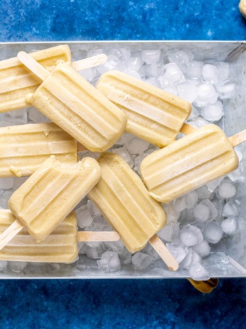 banana popsicles laid flat in an aluminum tray.