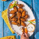 Air fryer frozen wings on a platter with carrots and celery and ranch dressing.