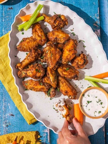 Air fryer frozen wings on a platter with carrots and celery and ranch dressing.