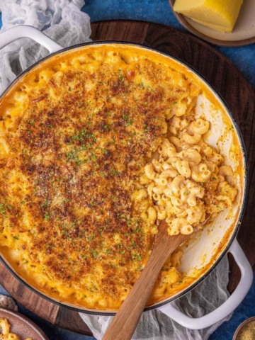 gouda mac and cheese on a flat surface garnished with breadcrumbs and herbs.