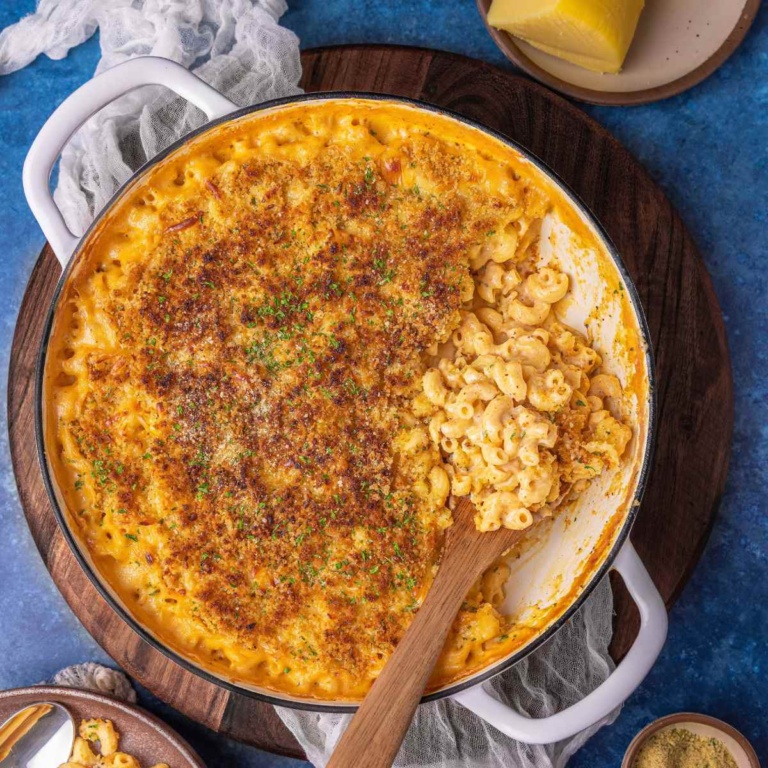 gouda mac and cheese on a flat surface garnished with breadcrumbs and herbs.