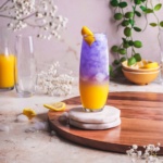 gin and orange juice in a tall glass garnished with lemon rind.