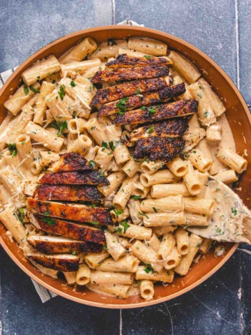 Chicken alfredo with blackened seasoning in a pan on a flat surface.
