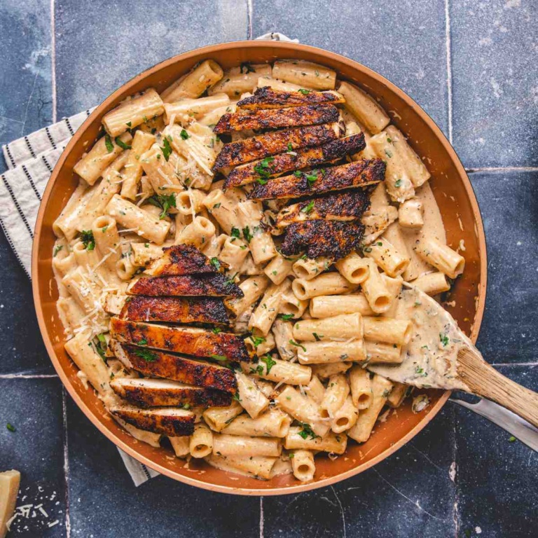 Chicken alfredo with blackened seasoning in a pan on a flat surface.