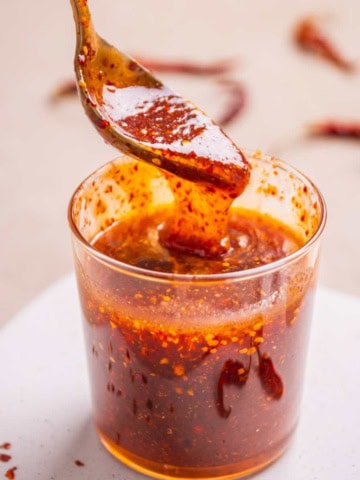 Hot honey sriracha sauce scooped in a spoon revealing texture and color.