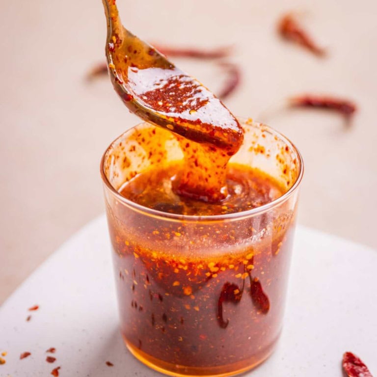 Hot honey sriracha sauce scooped in a spoon revealing texture and color.