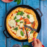 flatbread pizza margherita showing a slice of gooey melted cheese.