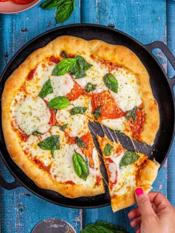 flatbread pizza margherita showing a slice of gooey melted cheese.