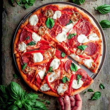 Italian pepperoni pizza on a table with basil.