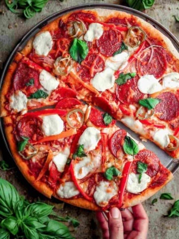 Italian pepperoni pizza on a table with basil.