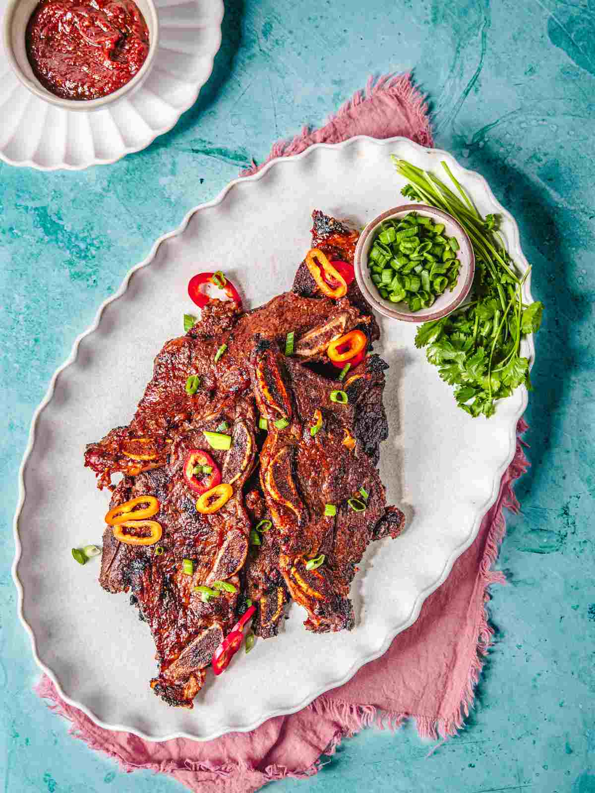 Beef short ribs with bbq sauce on a white plate.