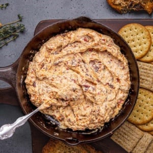 Baked Boursin dip with crackers on a wooden board.
