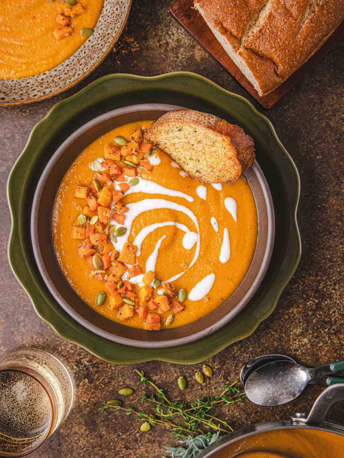 Butternut squash and carrot soup in a bowl garnished with baked squash and pumpkin seeds with a nice swirl of coconut cream.