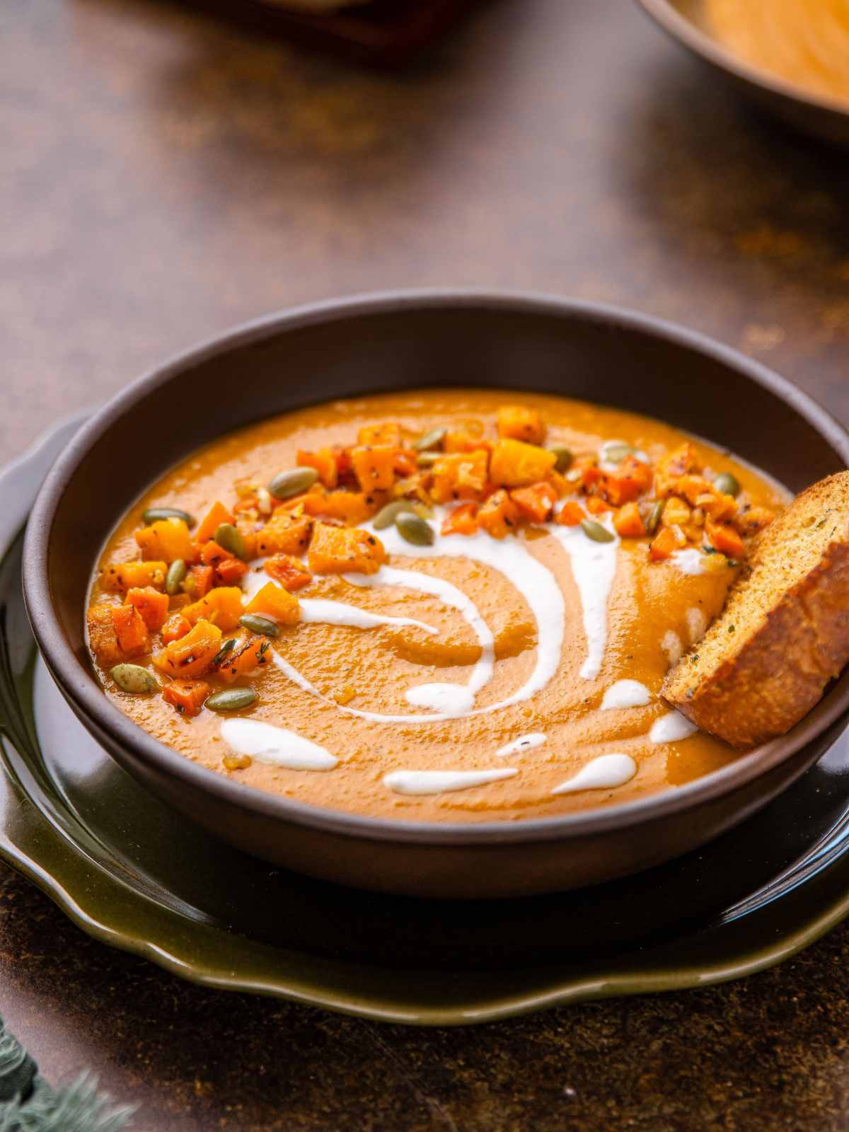 Pureed soup with oven roasted squash cubes and pumpkin seeds.