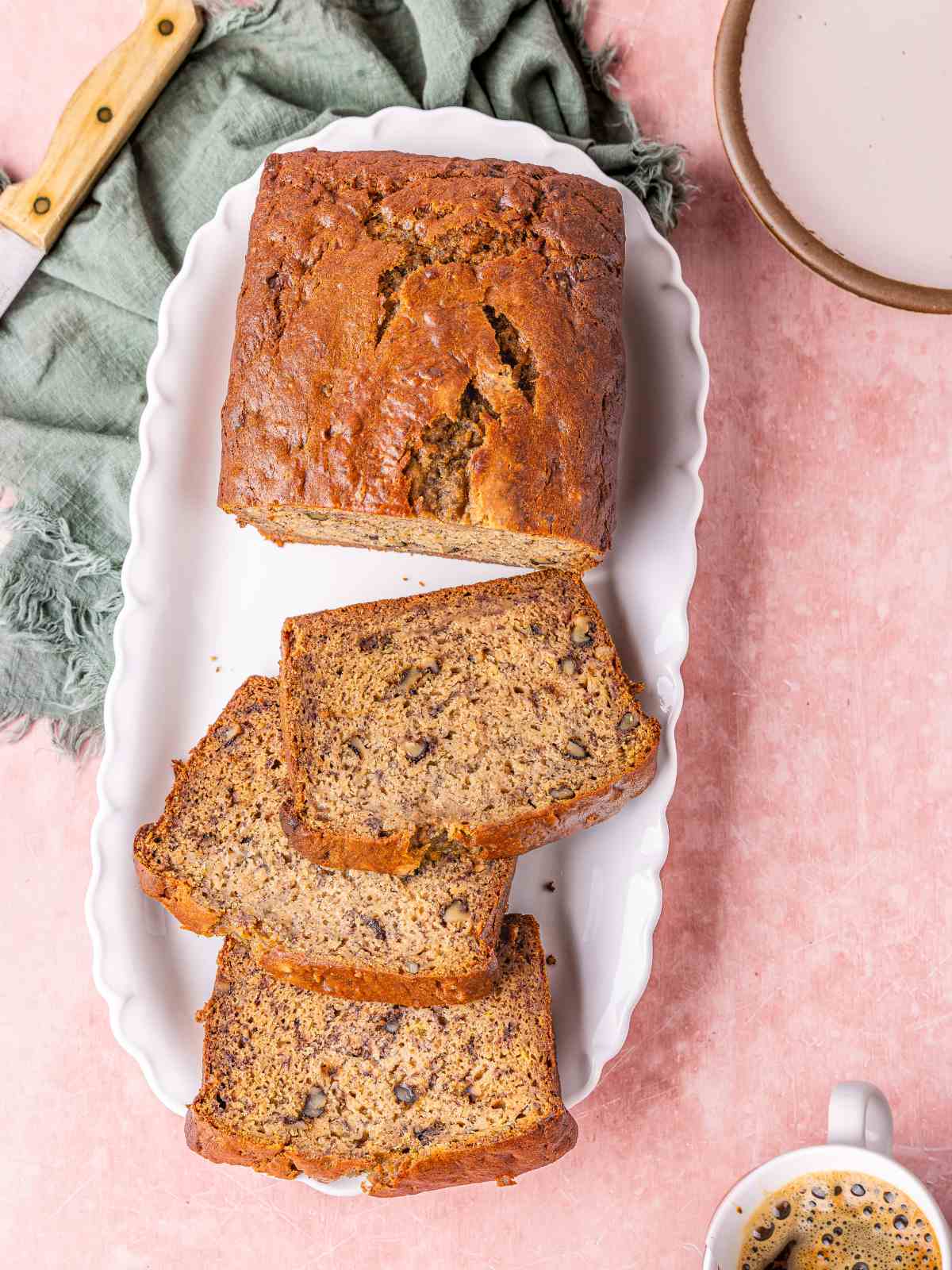 High protein banana nut bread on a white plate with coffee on the side.