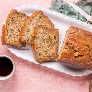 High protein banana nut bread on a platter served with coffee.