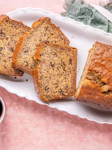 High protein banana nut bread on a platter served with coffee.