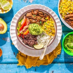 Steak and rice bowl on a flat surface.