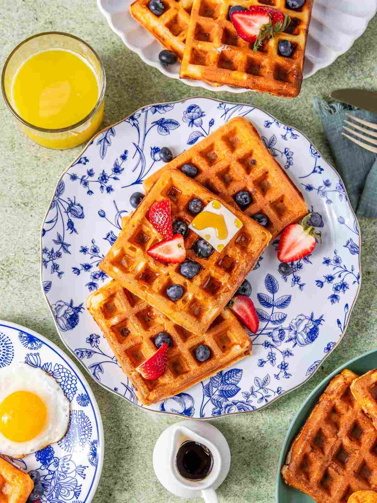 high protein waffles with strawberries, served with eggs and juice.