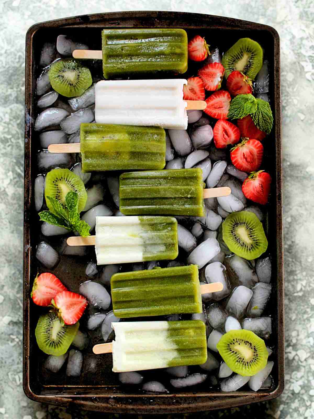 Coconut and kiwi popsicles on a tray.
