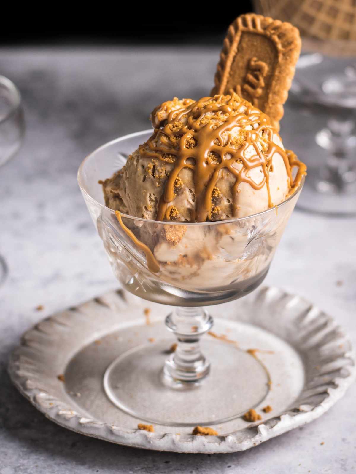 cookie butter ice cream in a serving cup with drizzles of biscoff butter and cookies.