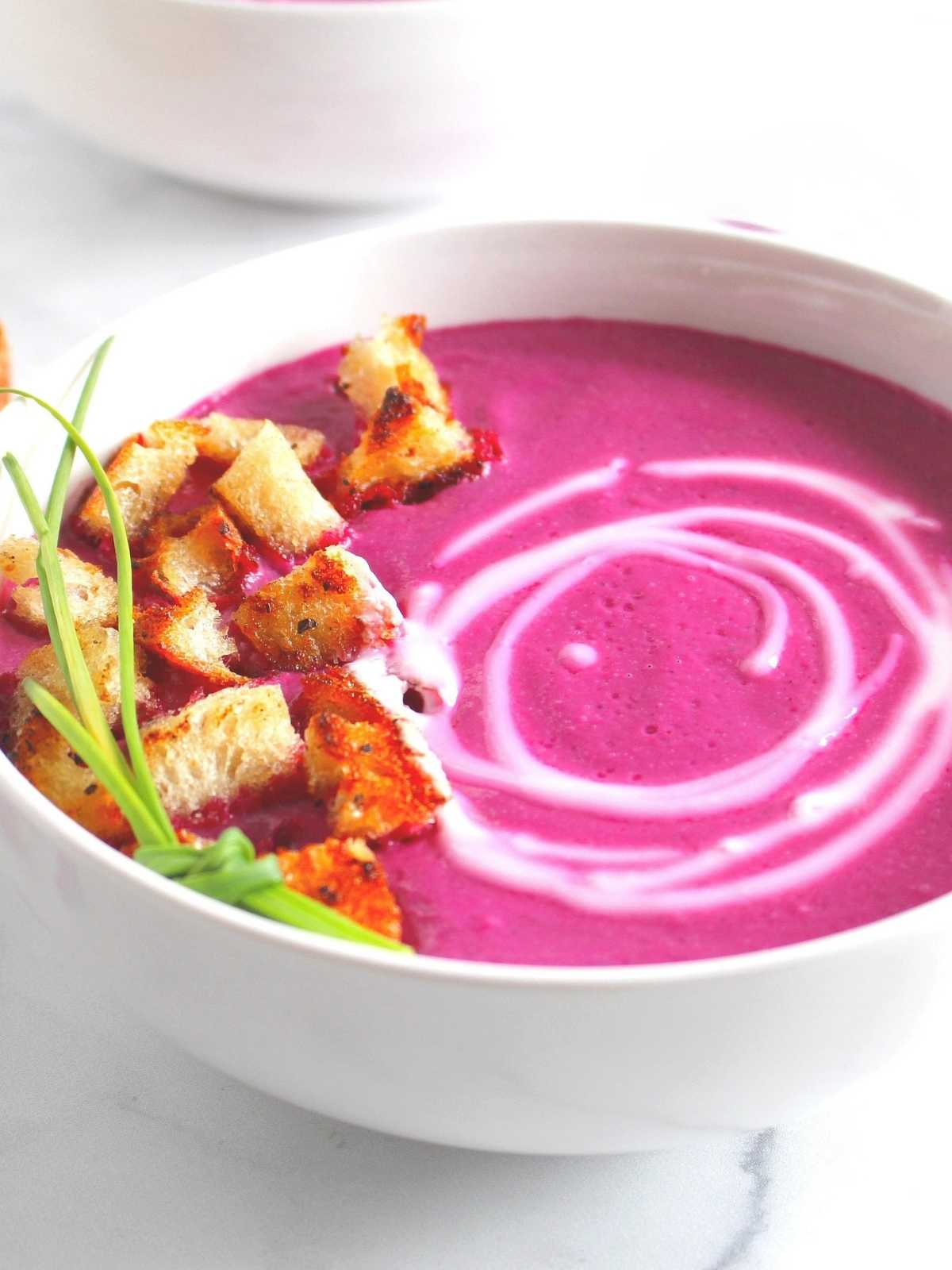 Beets, cauliflower and leek soup in a bowl with croutons.