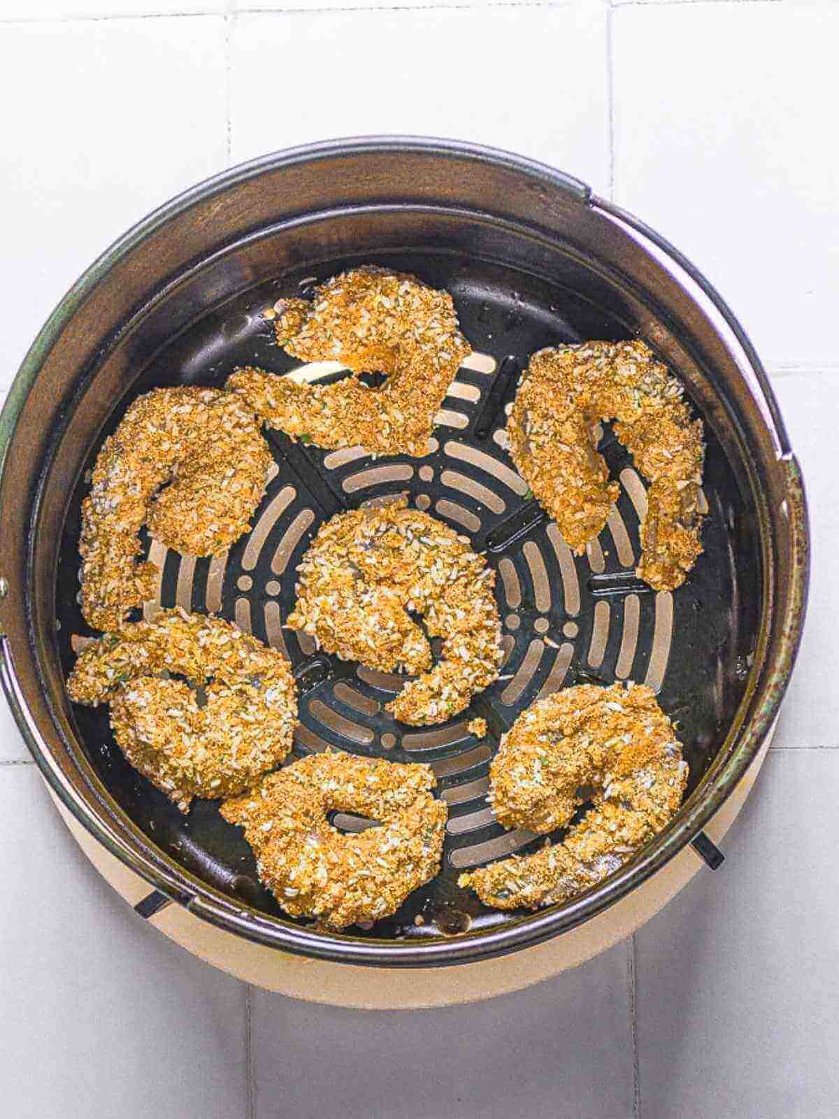 Coated shrimp in air fryer basket.