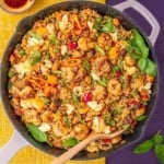 Shrimp and chicken fried rice in a pan with fresh basil.