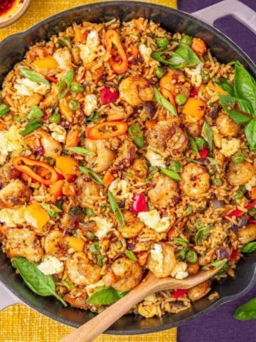 Shrimp and chicken fried rice in a pan with fresh basil.