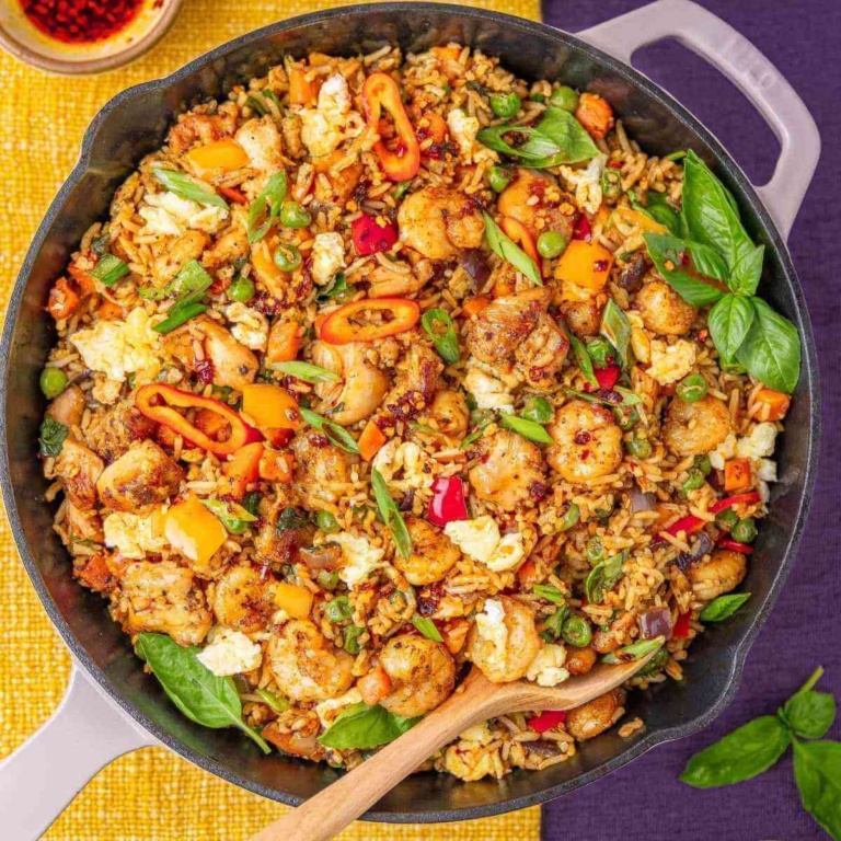 Shrimp and chicken fried rice in a pan with fresh basil.