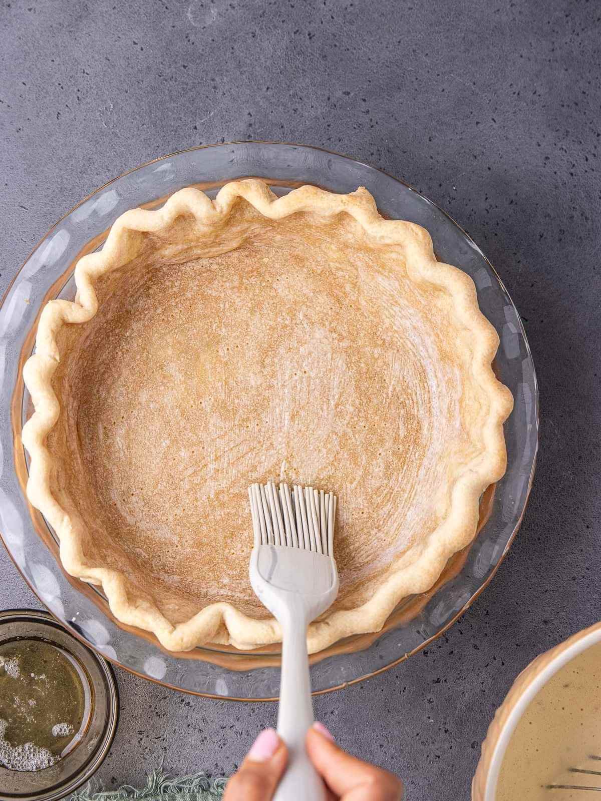 Sealing the pie crust with egg wash.