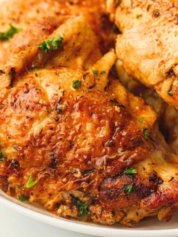 Instant pot chicken thighs in a white dinner plate.