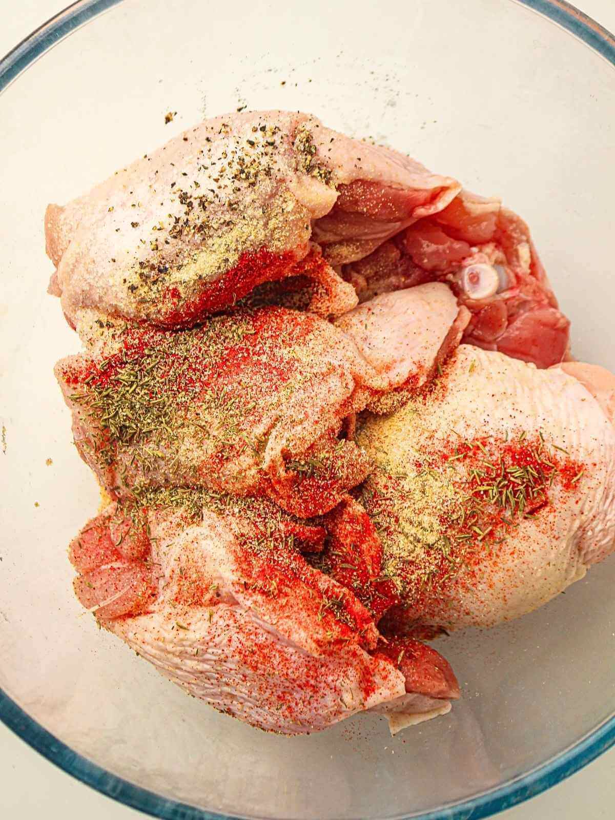 Seasoning the chicken thighs.